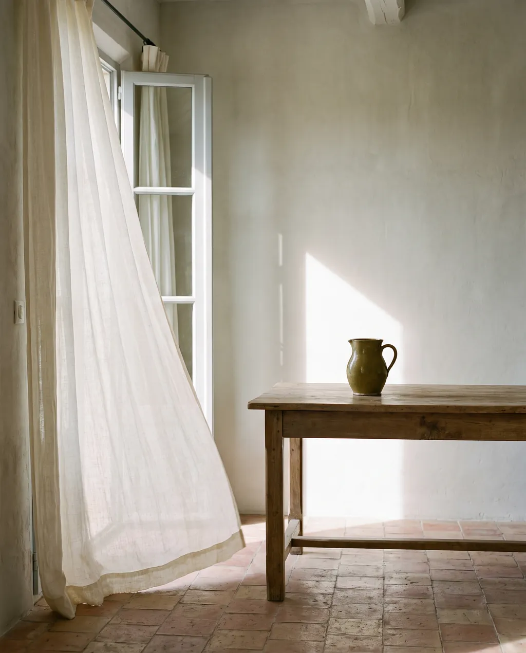 The interior of an empty Provencal villa in the morning, long linen curtains lifting